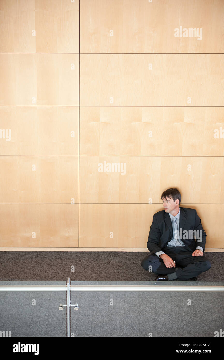 Businessman sitting in corridor Stock Photo