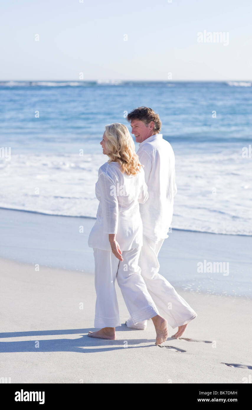 Couple walking along a beach Stock Photo - Alamy