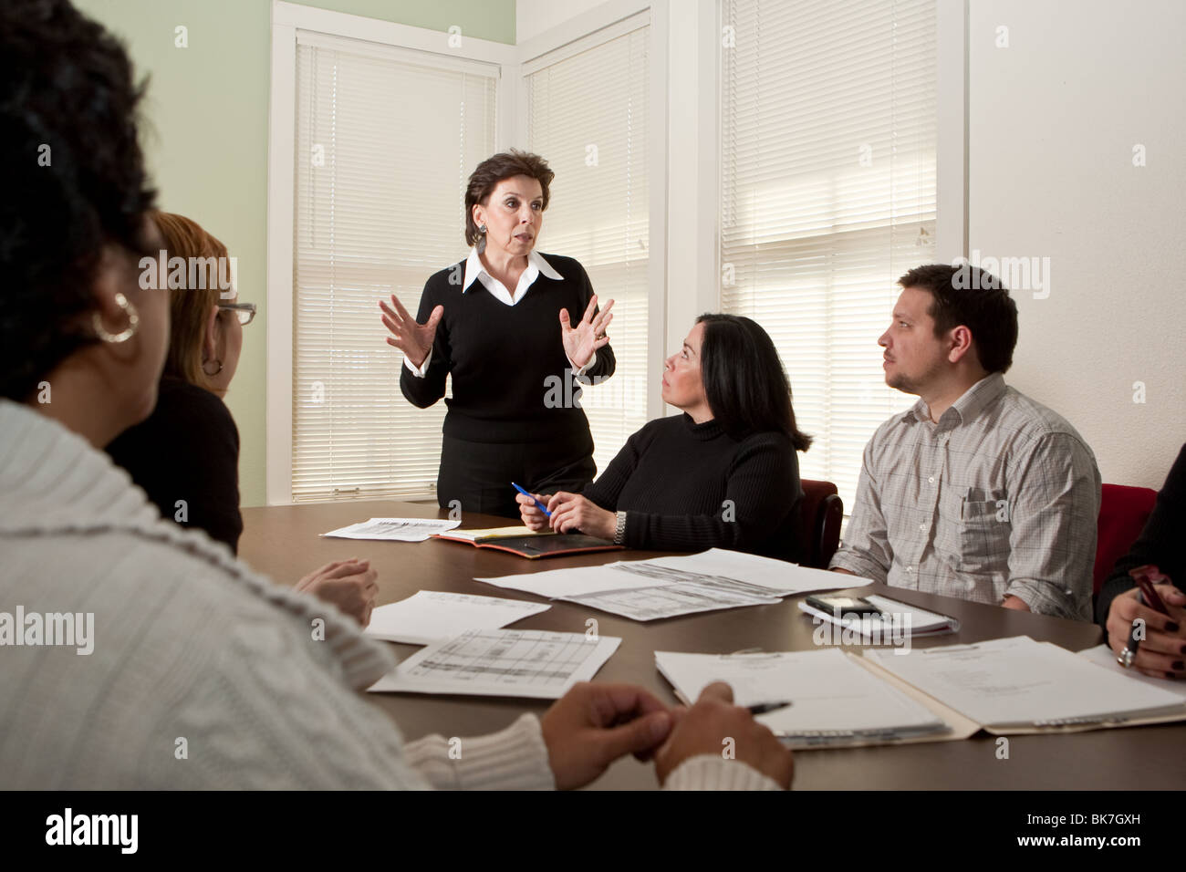 Female director of non-profit agency in San Antonio, Texas, conducts a staff meeting in the office conference room. Stock Photo