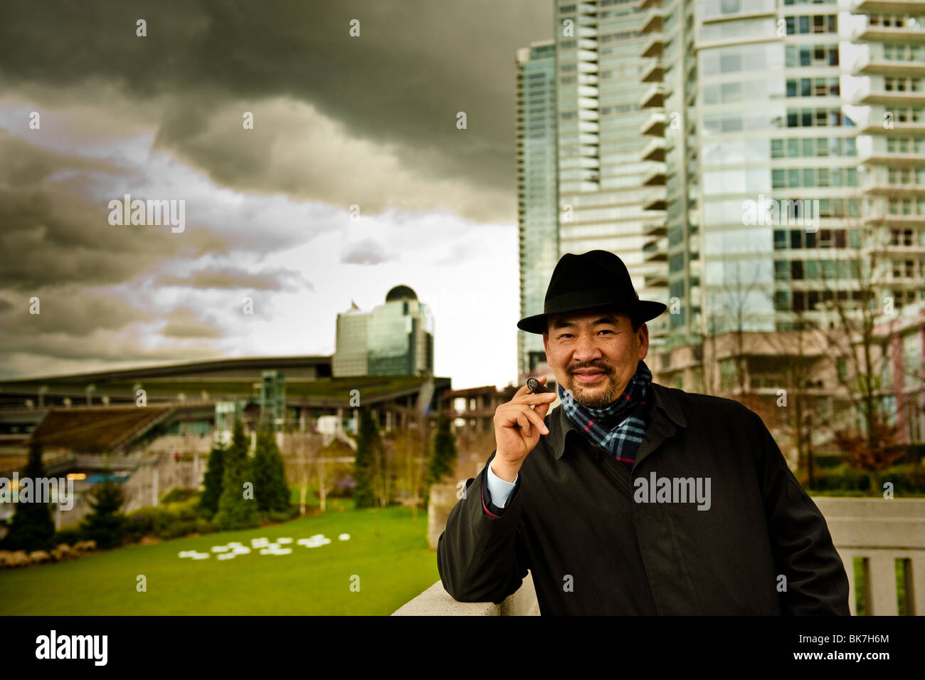 This is an image of an Asian man smoking a cigar in the city. Stock Photo