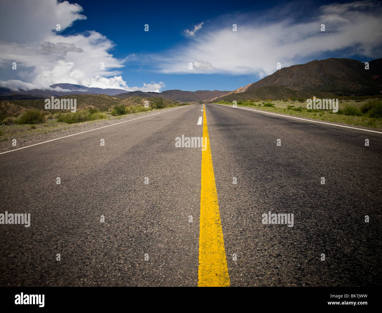 A desert road by the mountains surrounded by colorful nature. Stock Photo