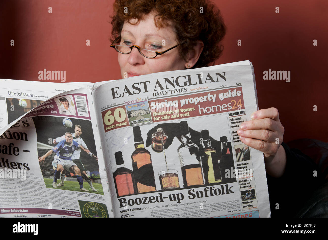 Woman at home reading The East Anglian Daily Times newspaper Stock Photo