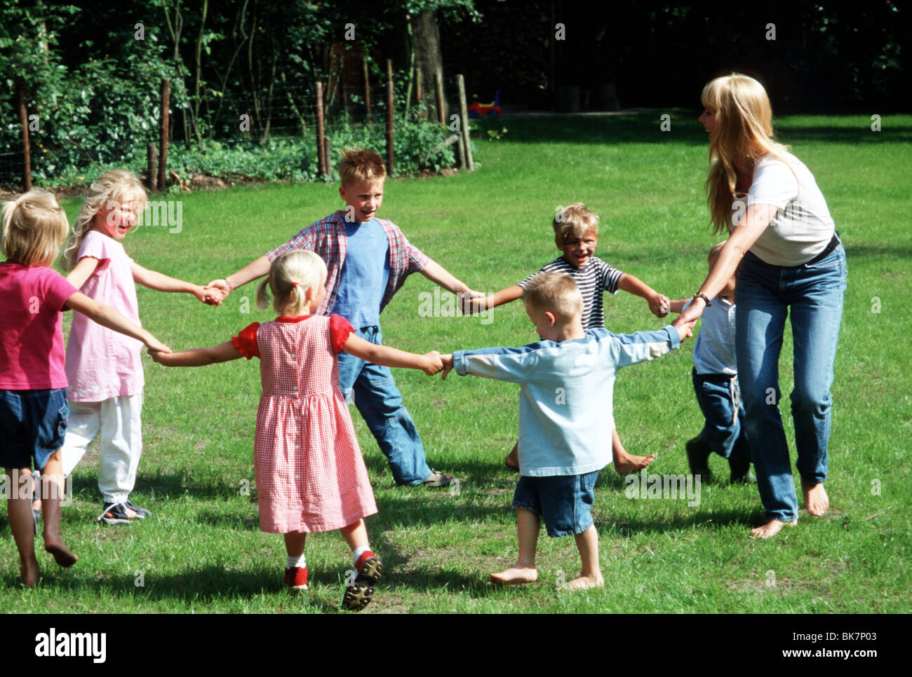 Childcare worker , day care facility, children playing outside game in