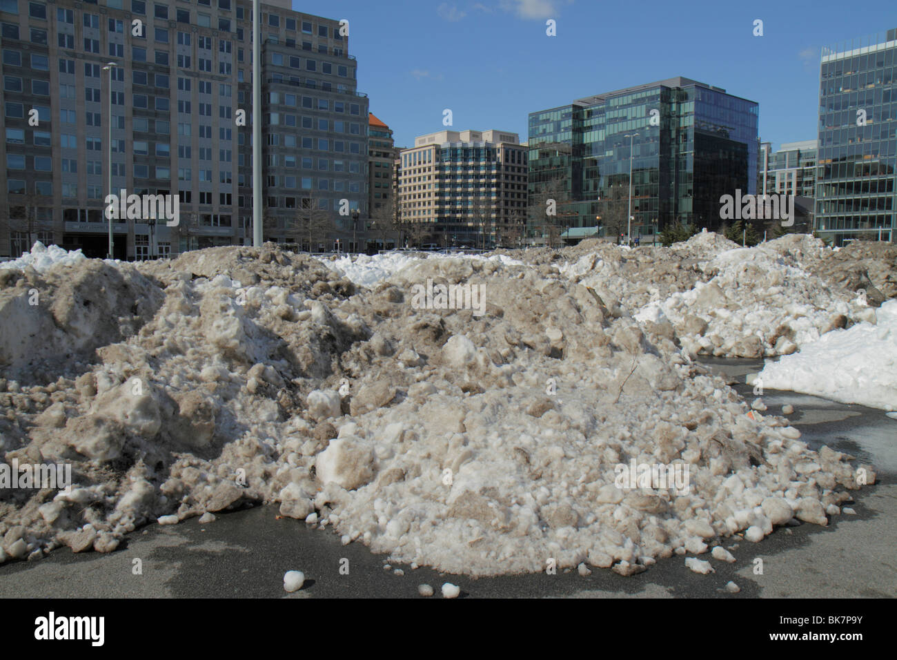 Washington DC,10th Street NW,dirty,grimy,snow,plowed,ice,thawing,melting,wet,pollution,winter,cold,weather,parking lot,office buildings,city skyline,r Stock Photo