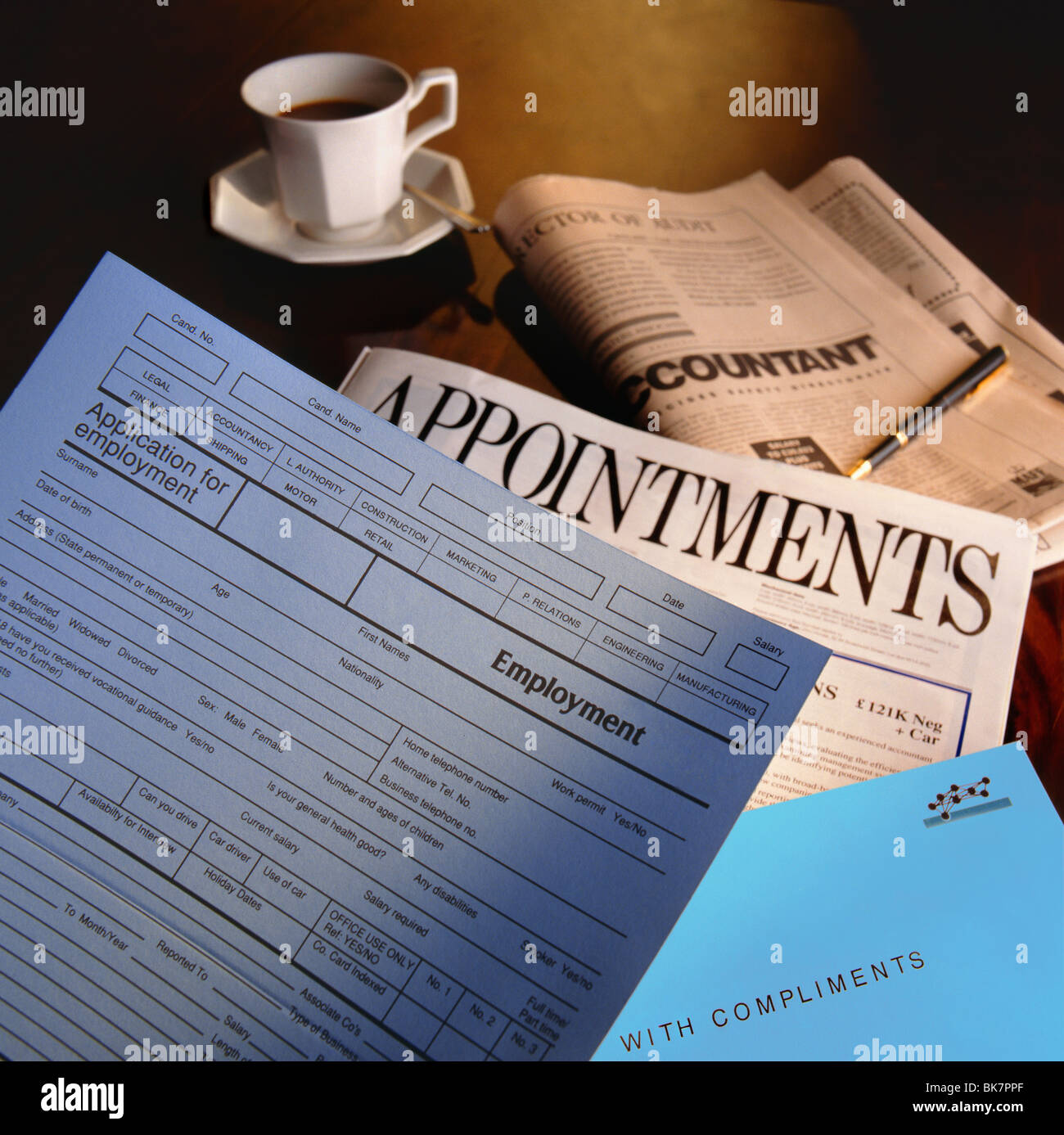 Job employment application form CV and newspaper appointments pages on desk with coffee cup