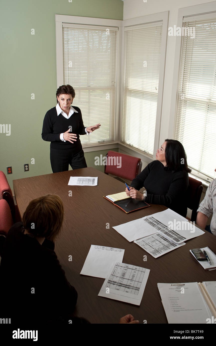 Female director of non-profit agency in San Antonio, Texas, conducts a staff meeting in the office conference room. Stock Photo