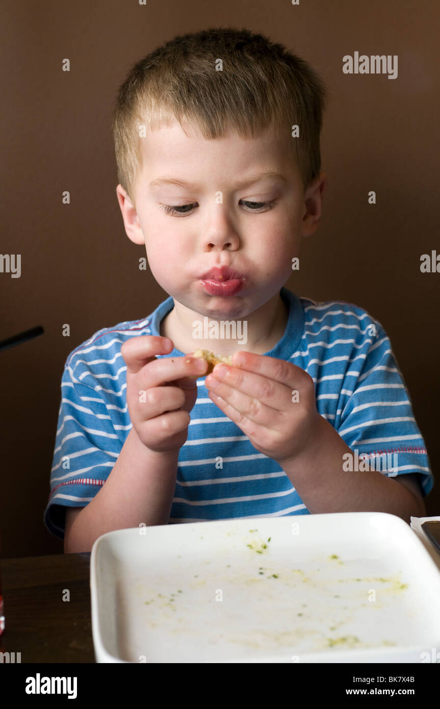 Young boy enjoying Garlic Bread at a Prezzo restaurant,empty plate,pursed lips,nutrition,enjoy,enjoyment,greasy fingers Stock Photo