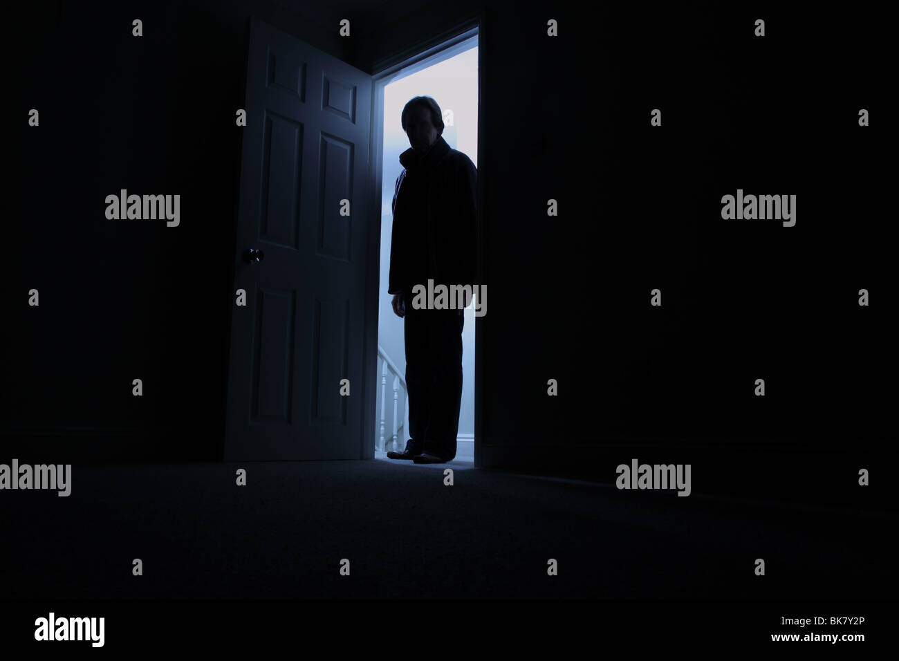 Man standing in the shadows of a dark room Stock Photo