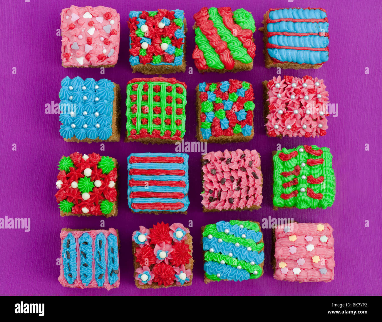 Homemade square individual iced cakes in a grid pattern. Flat lay