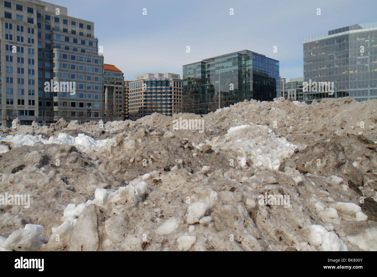 Washington DC,10th Street NW,dirty,grimy,snow,plowed,ice,thawing,melting,wet,pollution,winter,cold,weather,parking lot,office buildings,city skyline,p Stock Photo