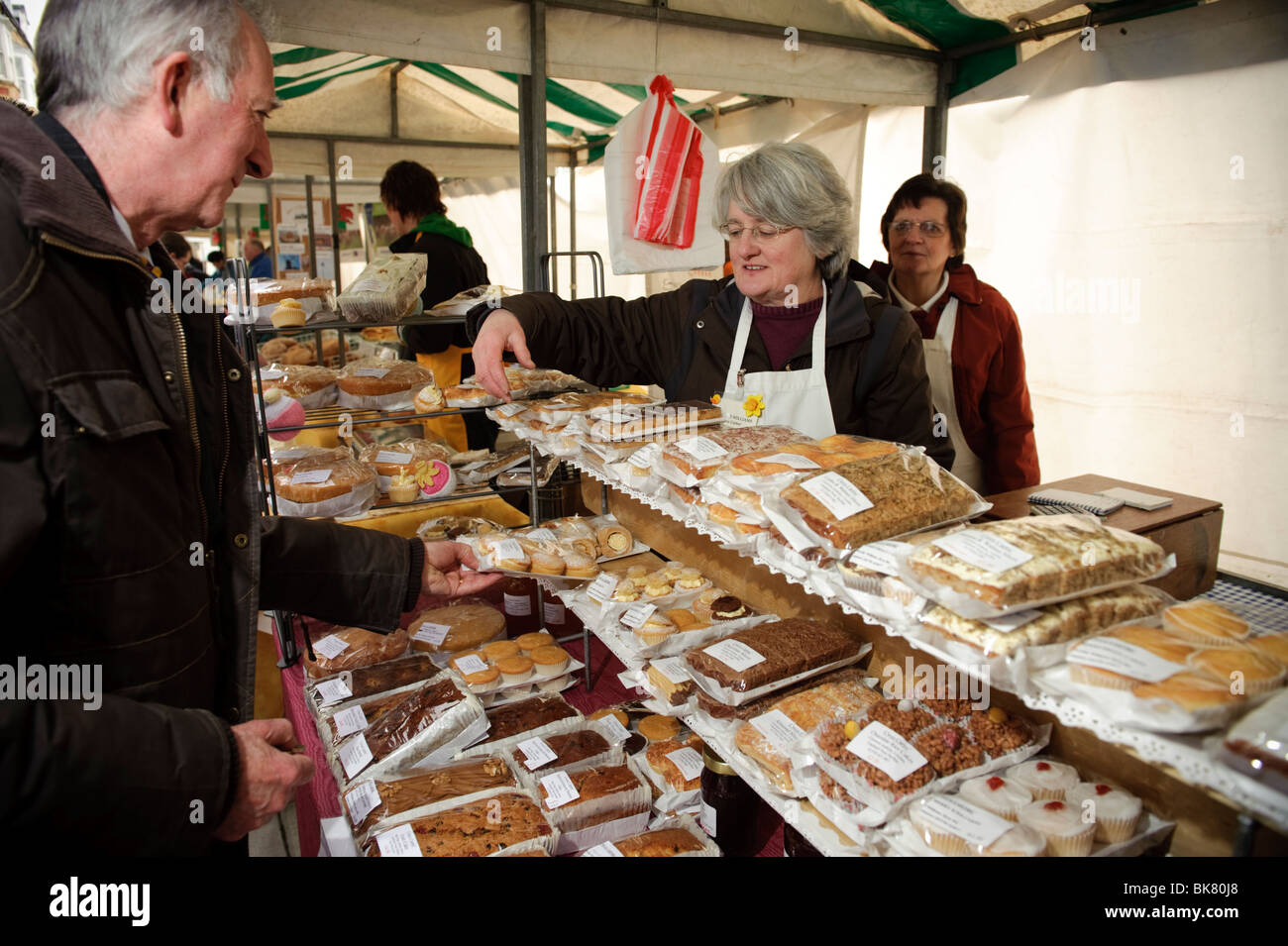 A man buying fresh home made cakes from a market stall on Aberystwyth Farmers Market, Wales UK