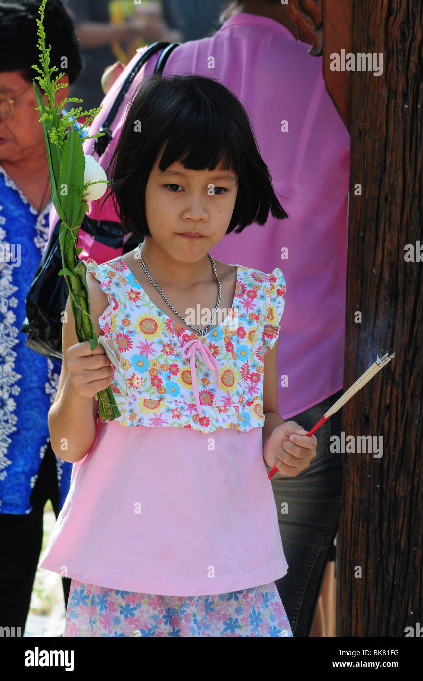 Young girl carrying offerings at Buddhist temple Stock Photo