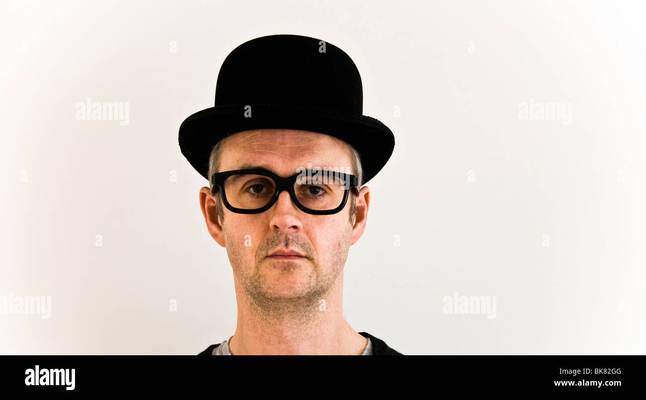 Middle aged man with serious expression in bowler hat and oversize glasses looking at camera. Concept of humour Stock Photo