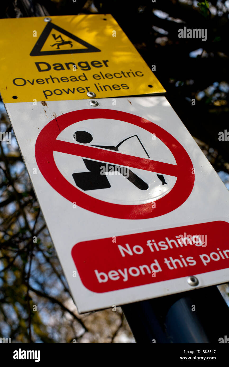 Sign warning river fishermen of overhead electric power lines, no fishing beyond this point. Stock Photo