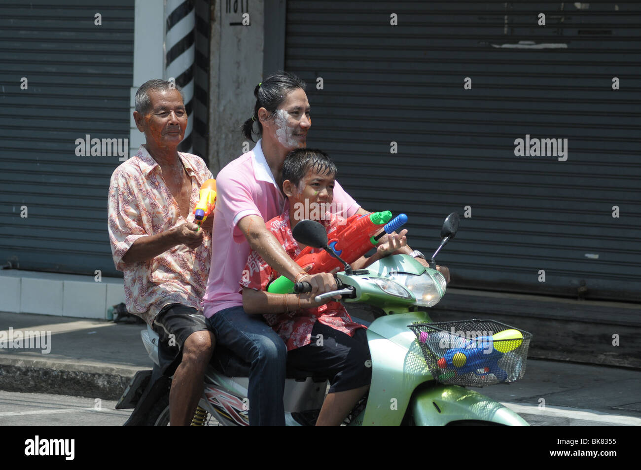 Three people on the back of a scooter during the Thai New Year or 'Songkran' fetsival Stock Photo