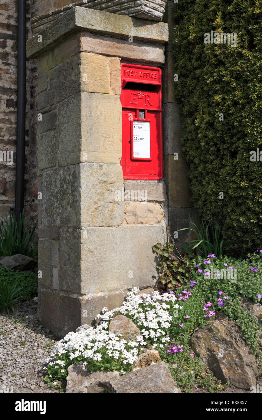 Red wall post box and spring flowers at Wensley, North Yorkshire