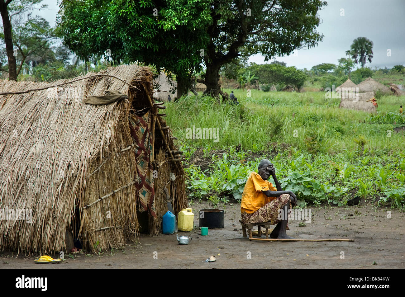 Worried old displaced woman sitting in front of her makeshift hut. She fled the lra conflict Stock Photo