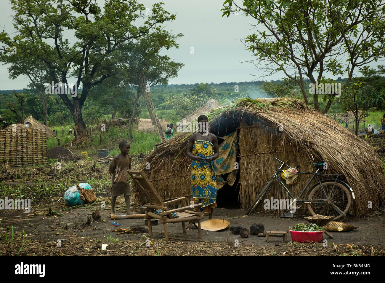 Refugees mother and son in their provisional shelter: a makeshift leaf house. Stock Photo