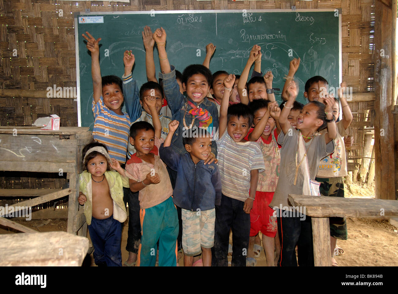 Poverty, developing country, education, primary school, pleasure, students stretching their hands up in front of the blackboard Stock Photo