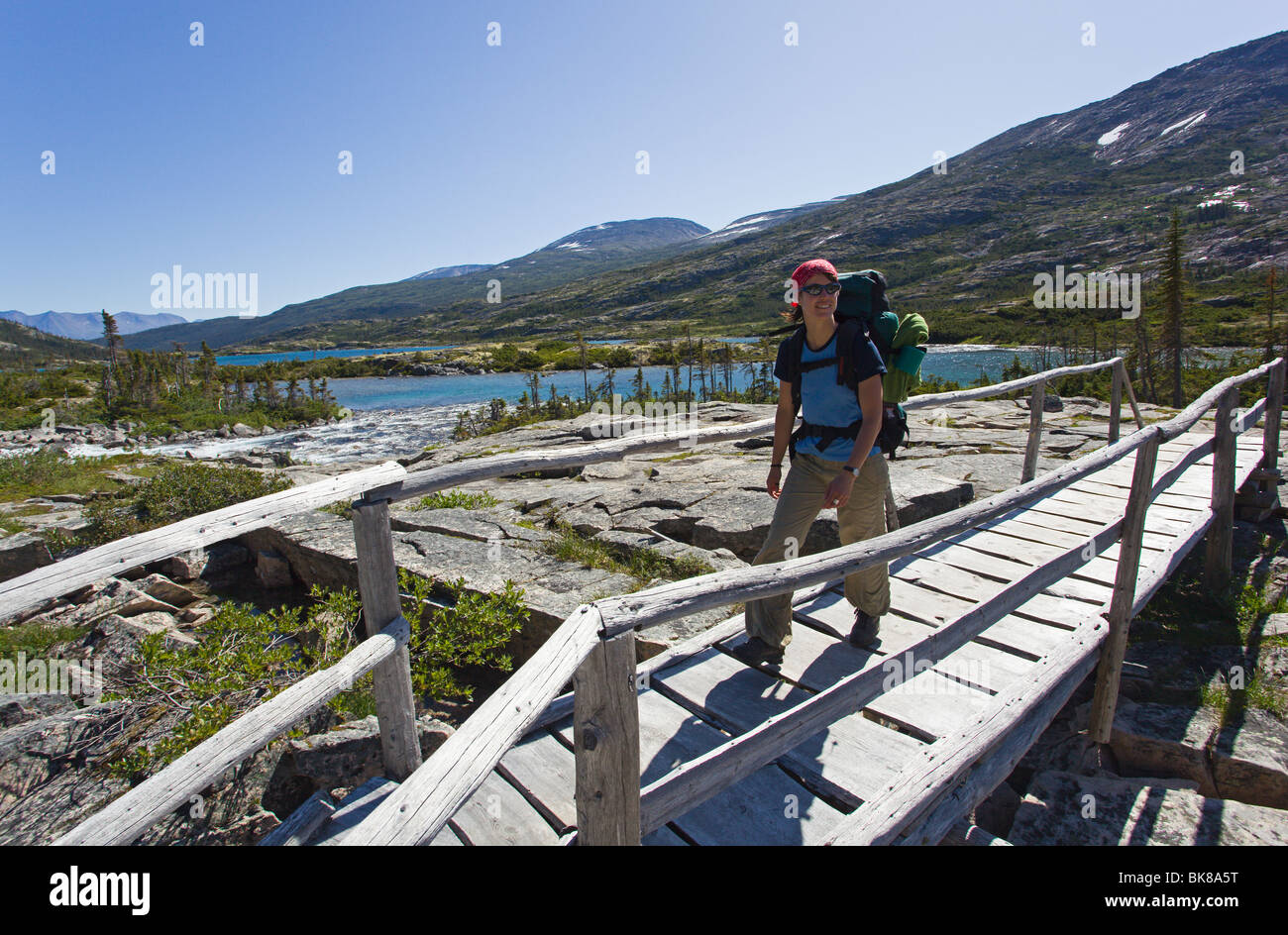 Young woman hiking, backpacking, crossing a wooden bridge, hiker with