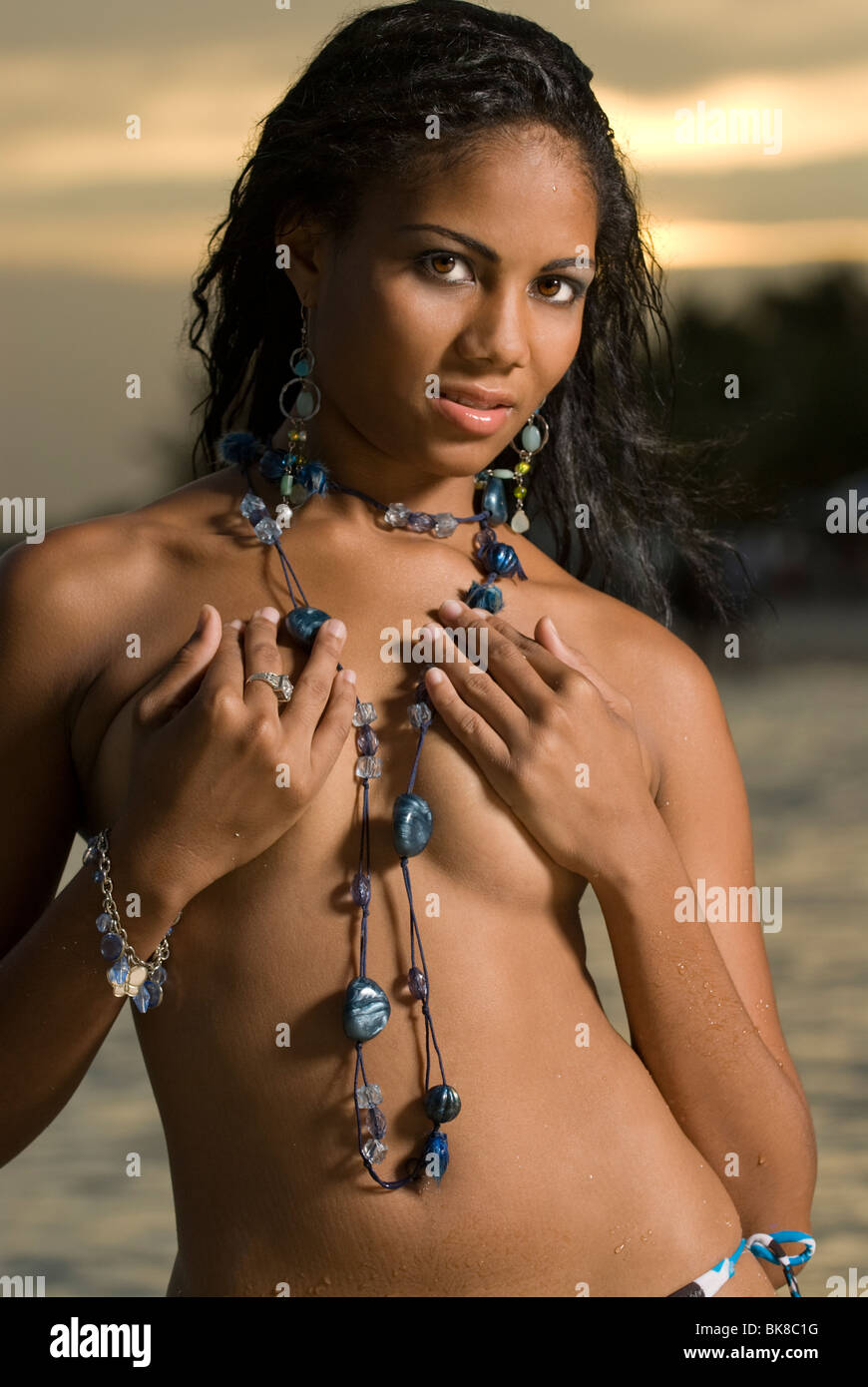 Beautiful young woman poses with beads and hands covering breasts Stock  Photo - Alamy