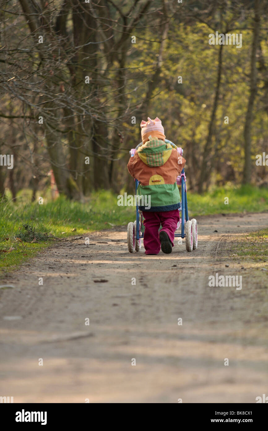 Girl walking with doll carriage Stock Photo