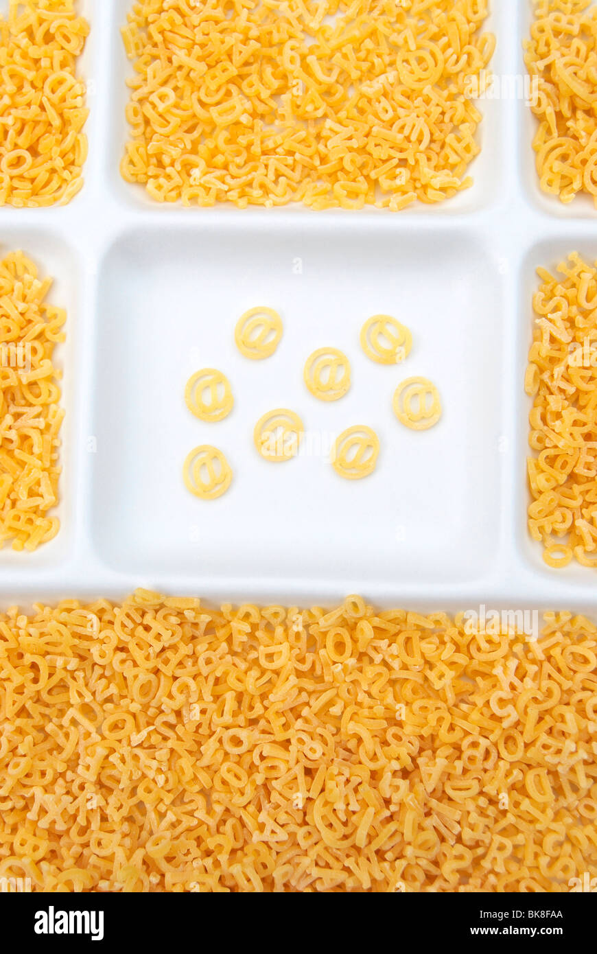 Letters made of pasta sorted and unsorted with special character @, plate Stock Photo