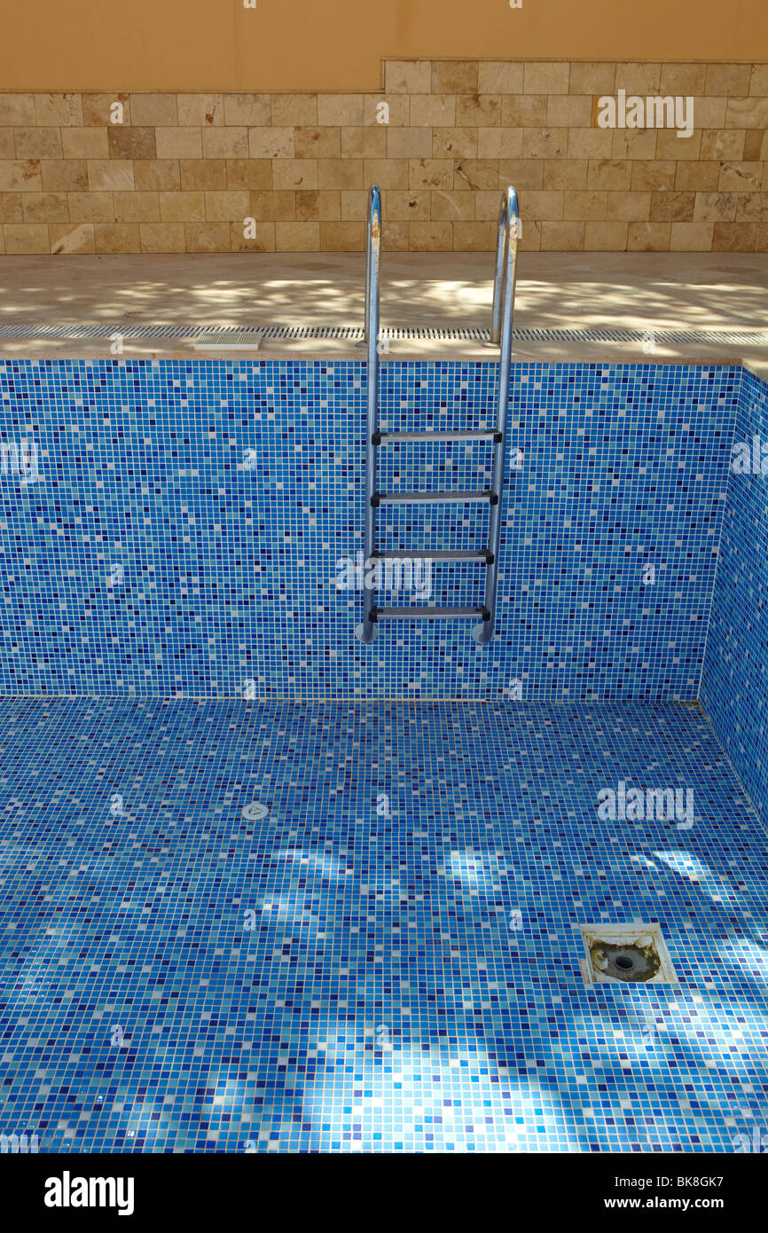 Blue tiled empty swimming pool on a sunny day without water Stock Photo