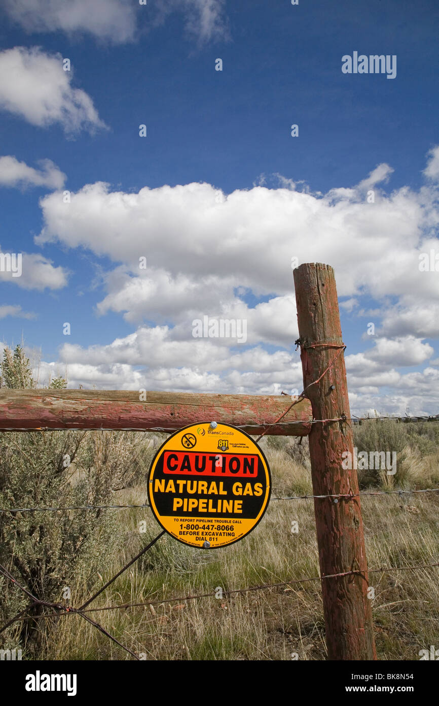 A caution sign on a barbed wire fence warns visitors about a Trans Canada Natural gas pipeline buried nearby, near Madras, Oregon. Stock Photo