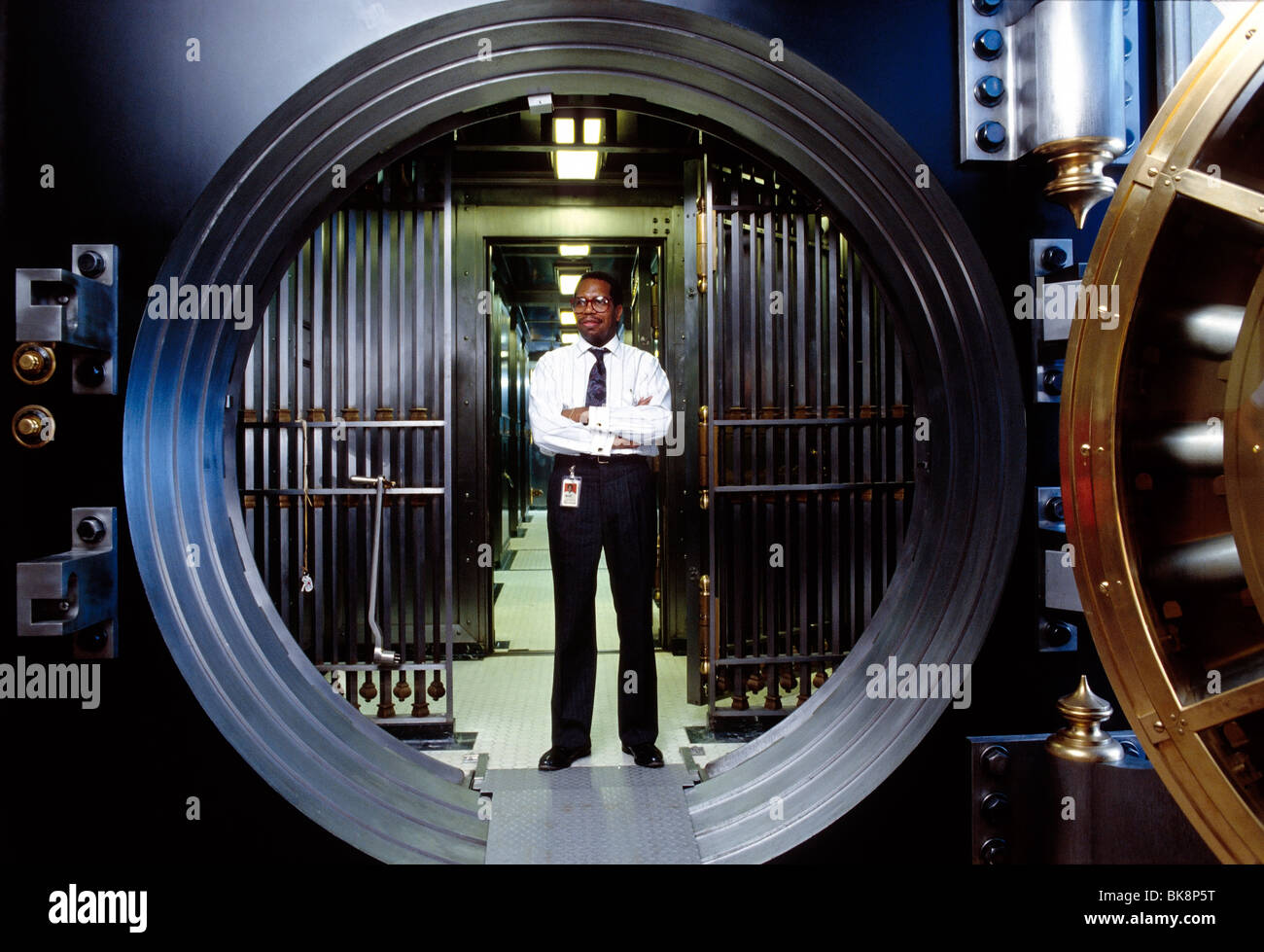 African American bank employee standing in the secure doorway to a large vault Stock Photo