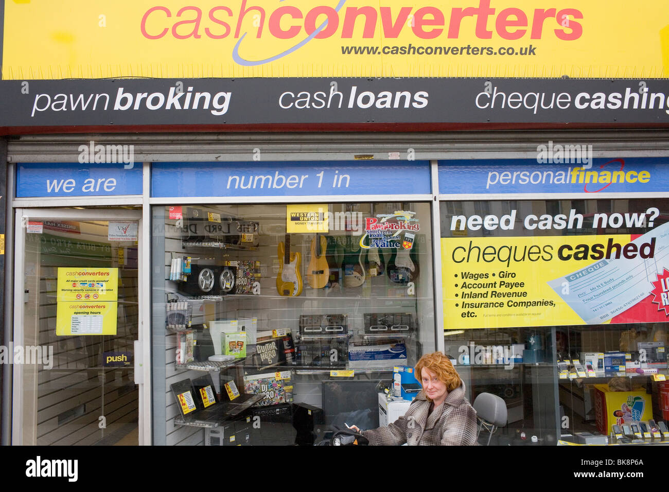 A woman in a mobility scooter sits outside 'Cash Convereters' on the Heathway, Dagenham's main shopping street. Stock Photo