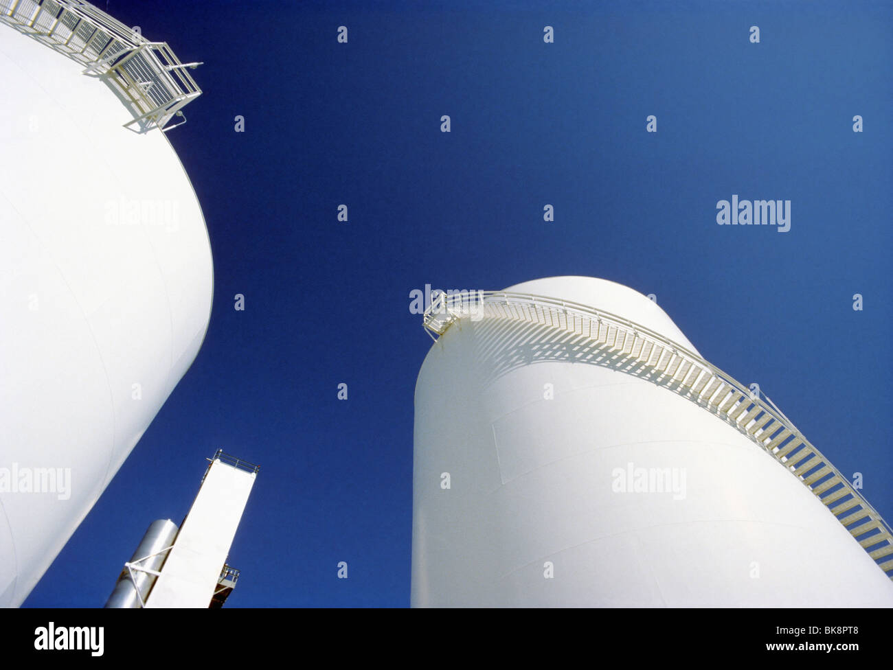 Large white metal storage tanks against a blue sky are used to store liquified gases. Stock Photo