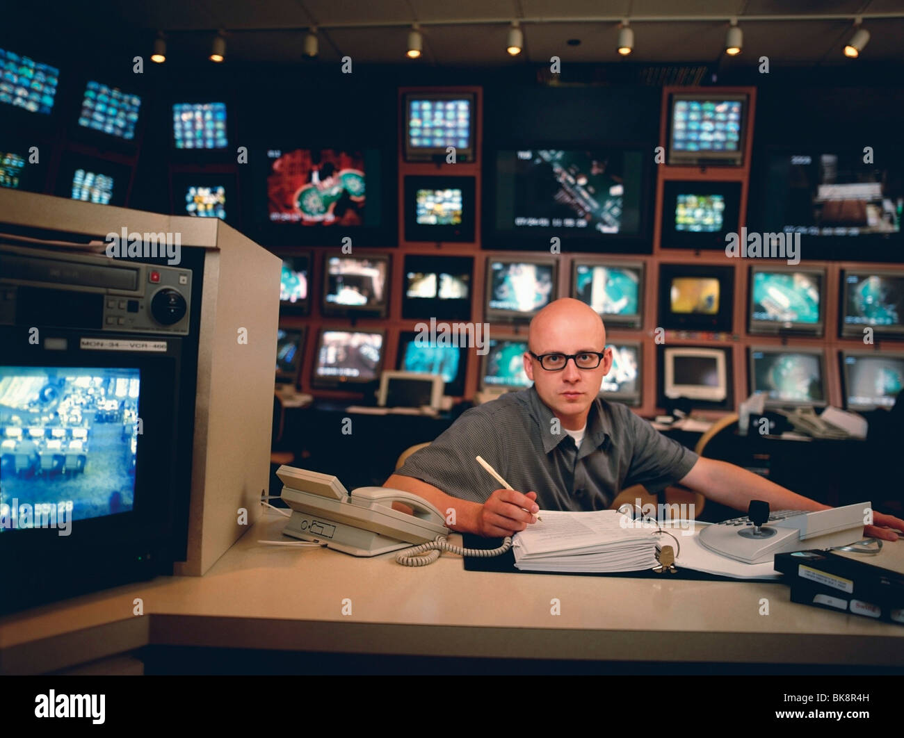 Man Sitting At Desk Surrounded By Security Videos In A