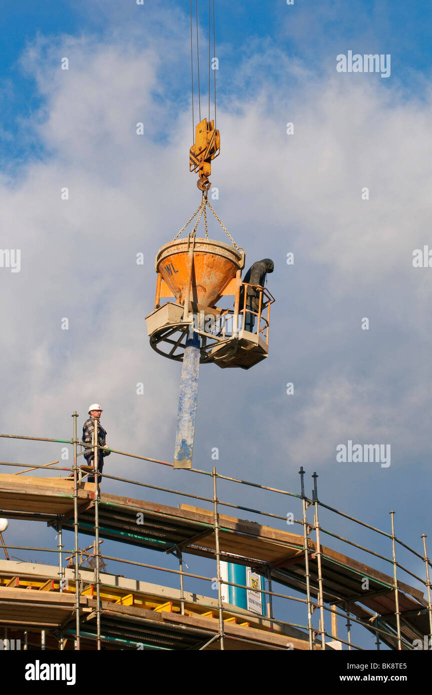 Construction worker standing on a concrete bucket and hose being