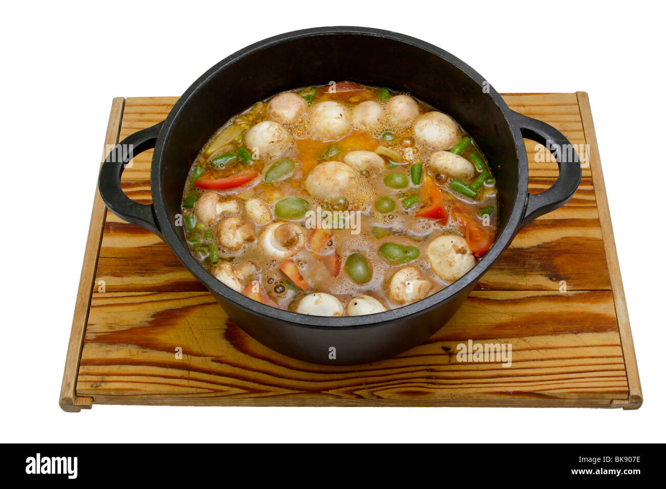 A hearty stew being prepared in a cast-iron pot, isolated on a white background. Stock Photo
