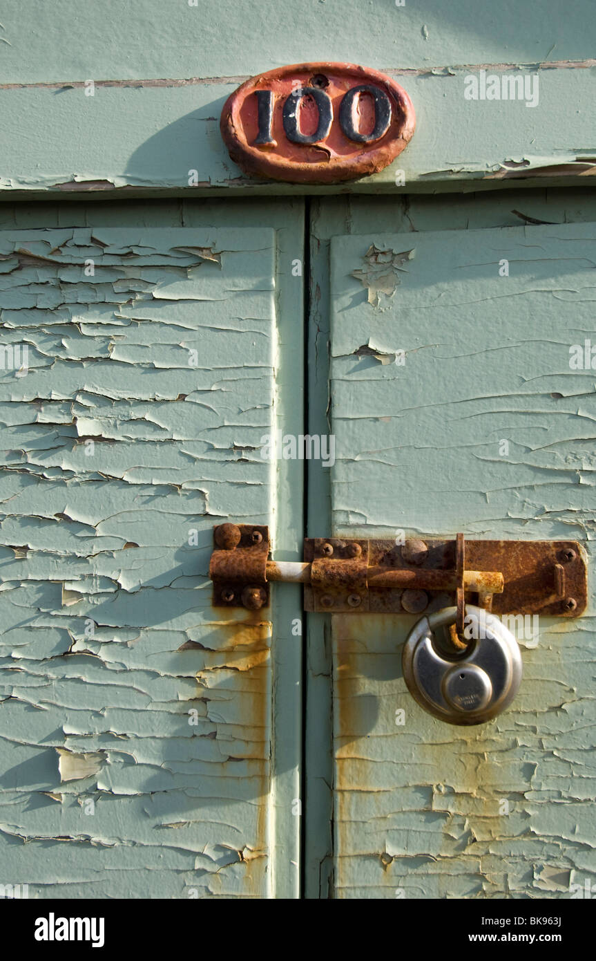 A beach hut, number 100, on Hove Esplanade, with its rusty bolt and padlock. Stock Photo