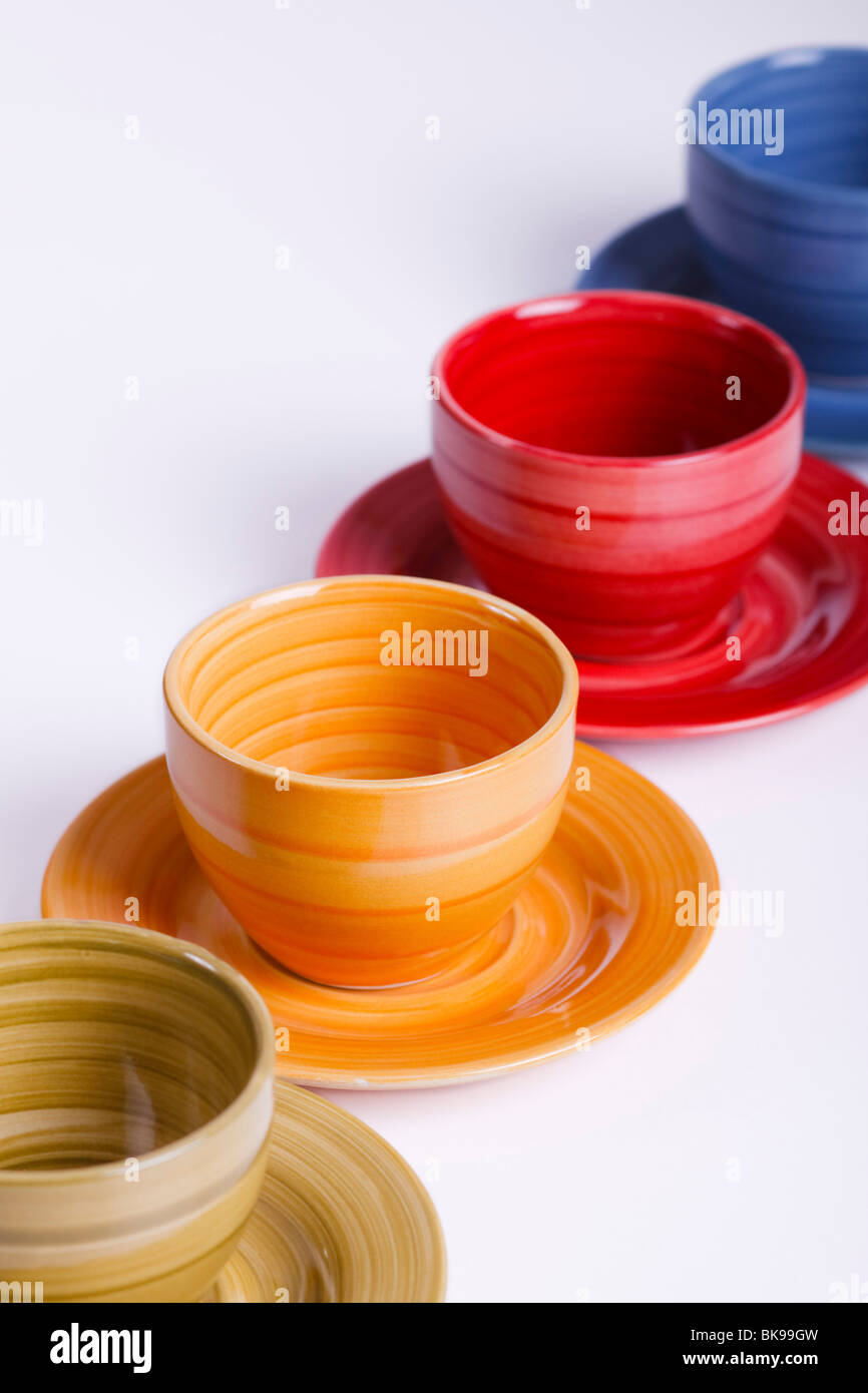 Four colourful tea cups lined up diagonally. Isolated. Stock Photo