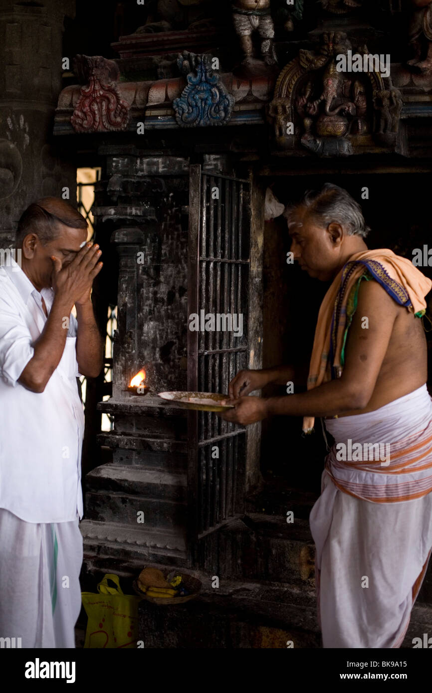 A priest by a shrine at the Murugan temple, gives ritual blessings to pilgrims in Swamimalai, India Stock Photo