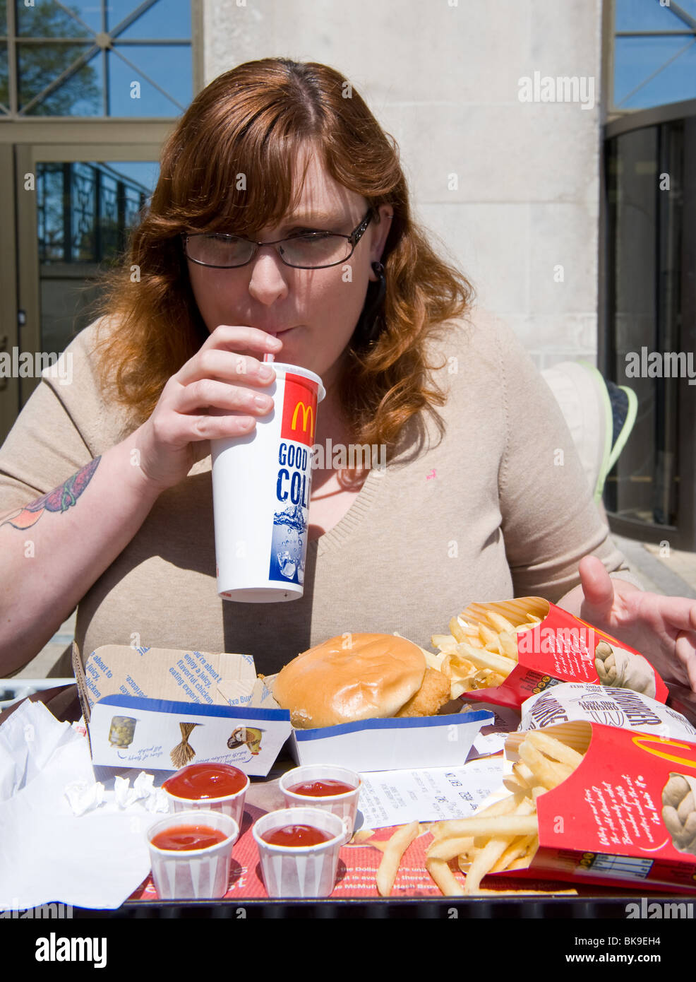 Overweight woman eating McDonald's fast food meal Stock Photo