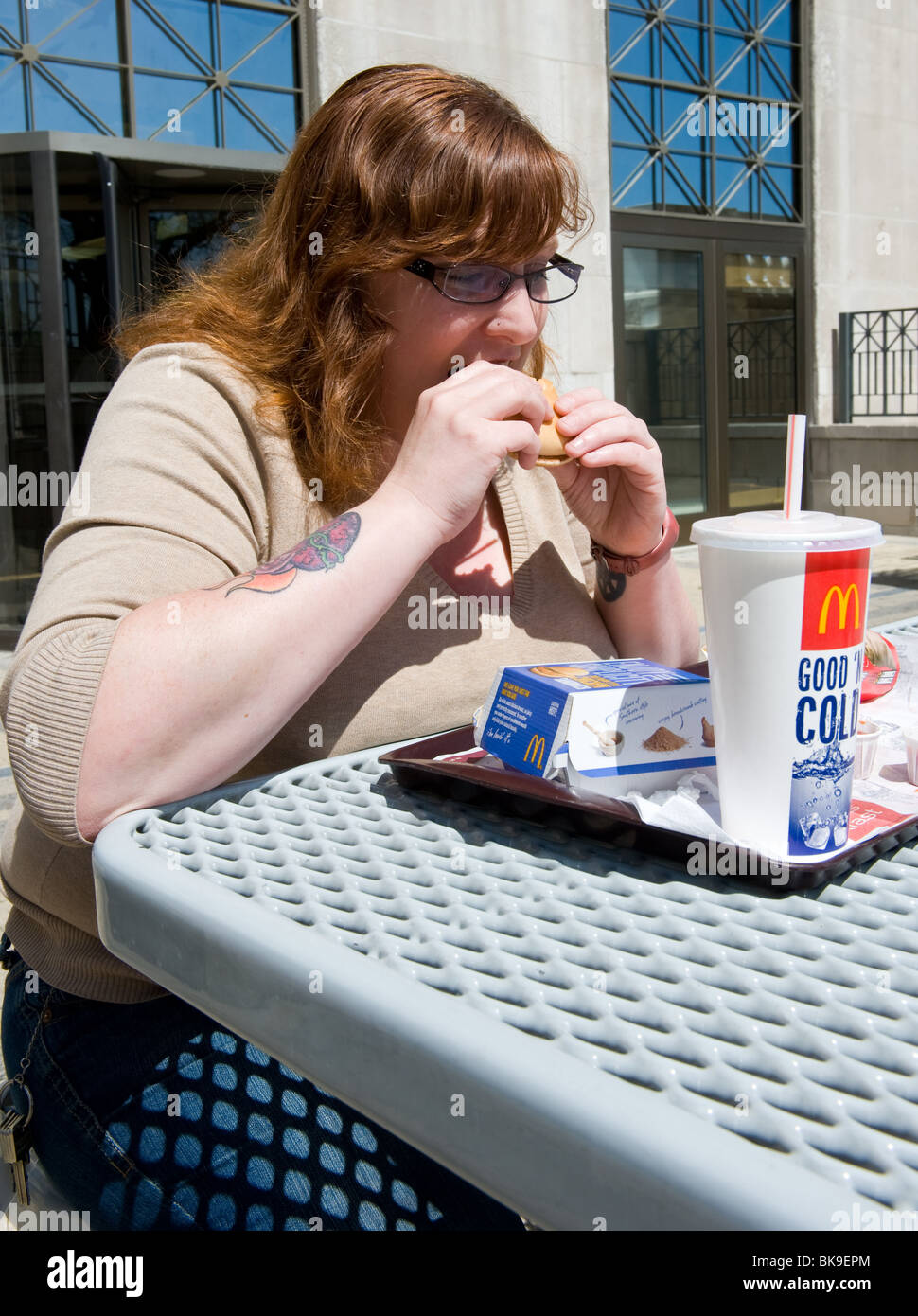 Overweight woman eating McDonald's fast food meal Stock Photo