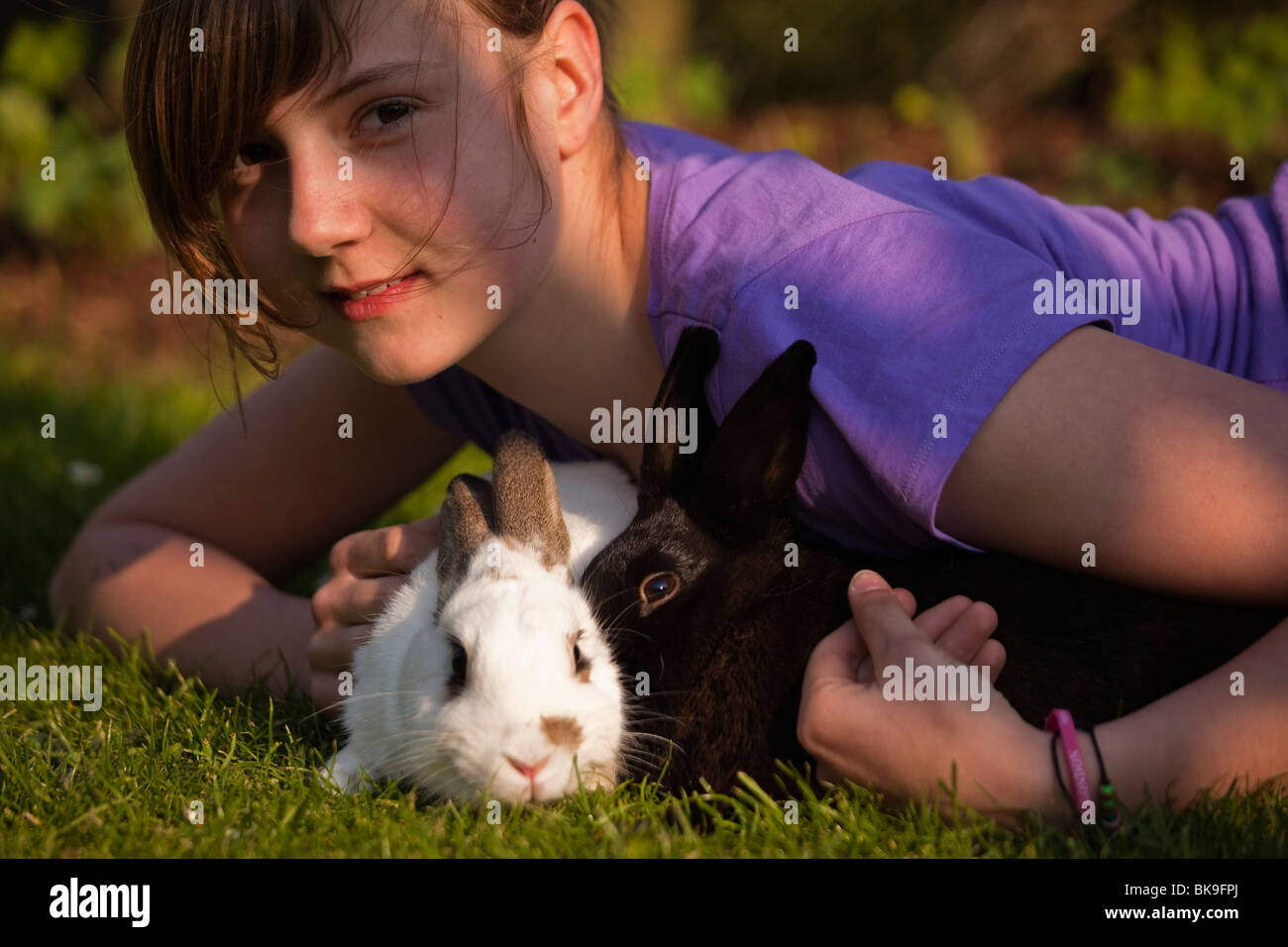 Young girl playing with two rabbits in a meadow Stock Photo Alamy