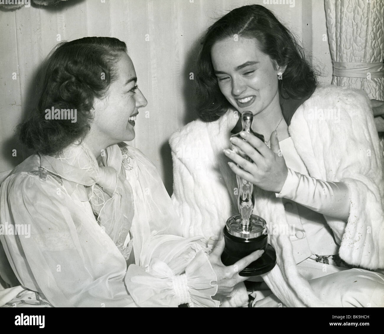 JOAN CRAWFORD at left with her Oscar for "Mildred Pierce" in 1945 shares her delight with Ann Blyth who won Best Supporting Actress in the same film. Crawford was still in bed having been too ill to attend the Oscar ceremony. Stock Photo