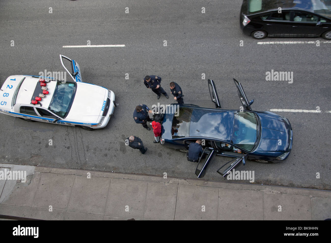 Police officers stop a car with two male suspects in New York City and search their car. Stock Photo