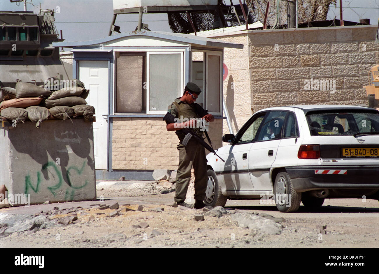 An Israeli soldier searches the car of a Palestinian man at a military checkpoint in the West Bank town of Bethlehem. Stock Photo