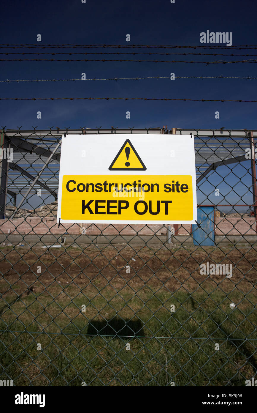 construction site keep out sign on a chain link fence surrounding a redevelopment brown field building site Stock Photo