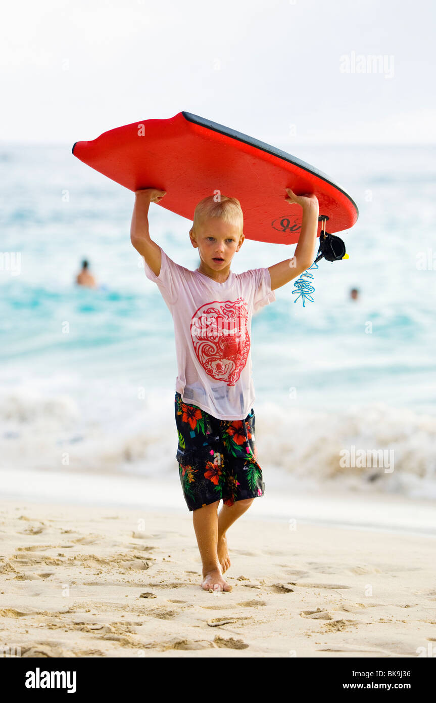 Young boy carrying his bodyboard hires stock photography and images