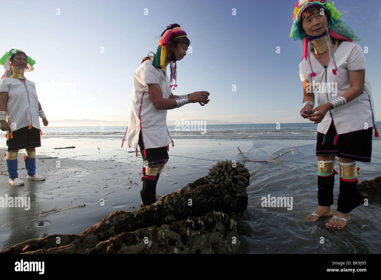 Kayan women Mu Li, left , Mu Phou and Mu La explore the beach in Nelson, New Zealand Stock Photo
