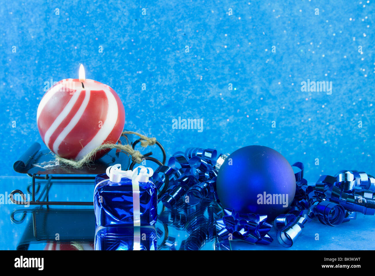 blue Christmas bauble, ribbon, present with red and white striped candle and copyspace Stock Photo