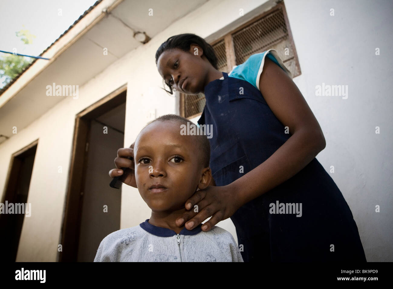 Woman combing a child's hair in an orphanage in Tanzania, East Africa Stock Photo