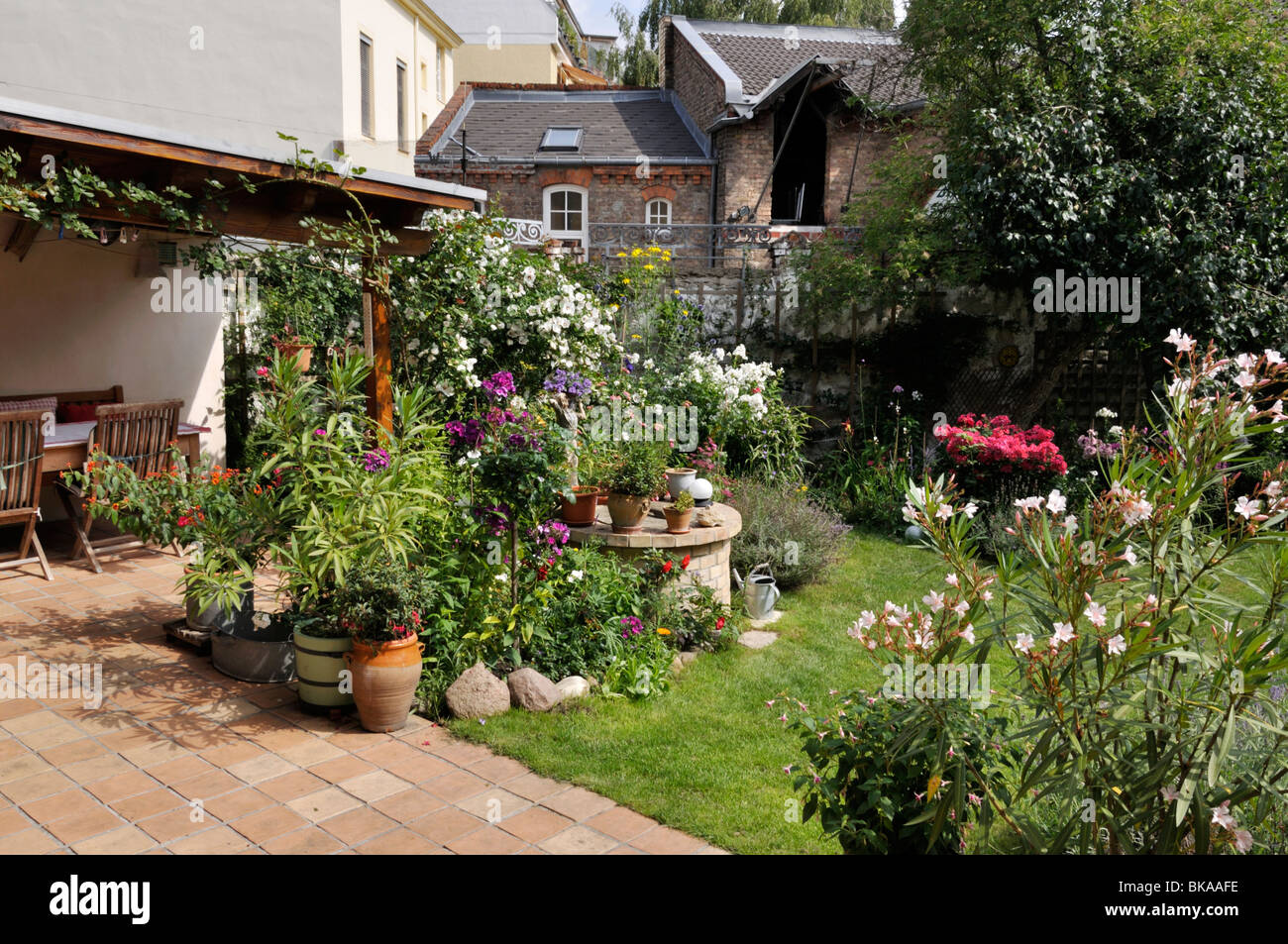 Backyard garden with perennial beds, lawn and terrace with potted plants. Design: Jutta Wahren Stock Photo